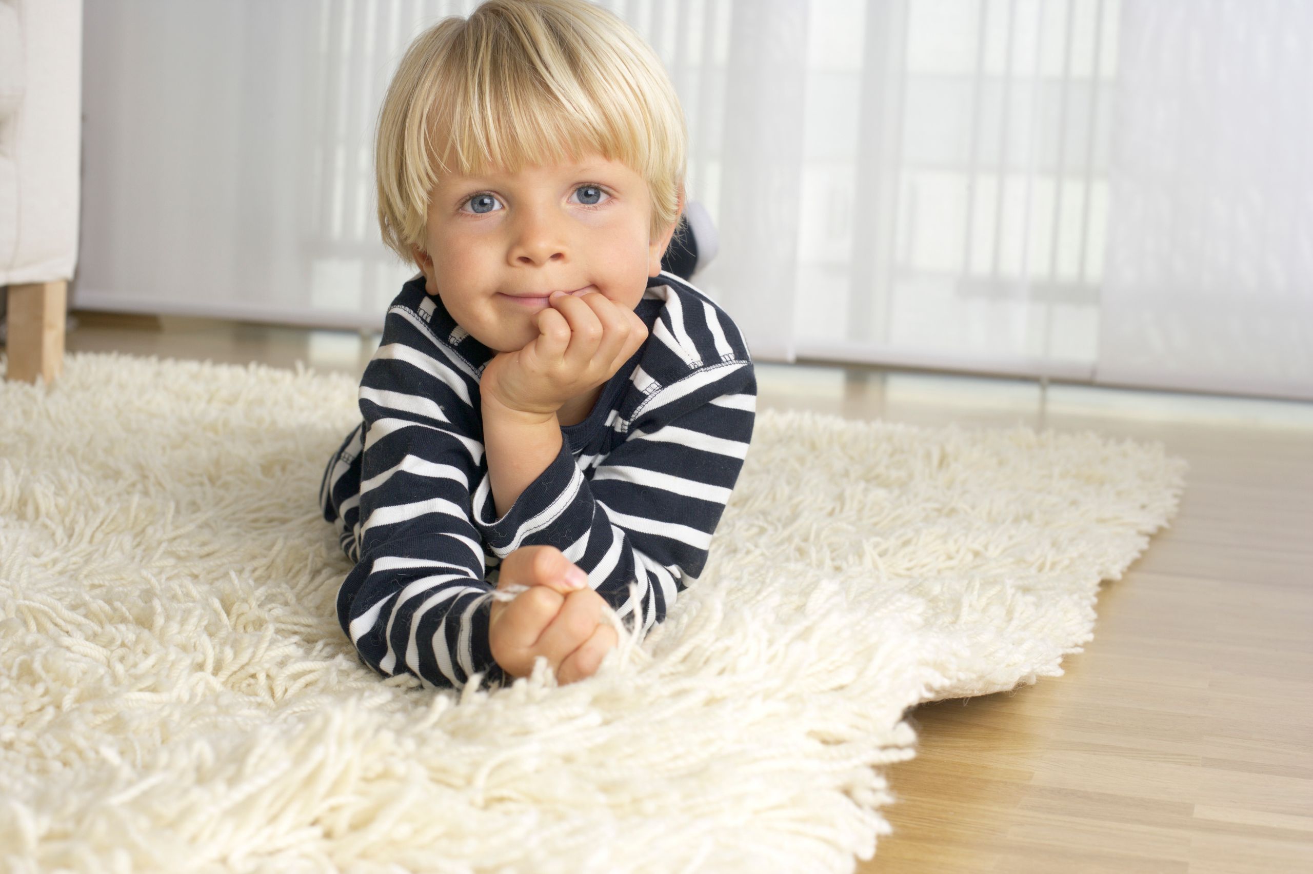 Young boy lying comfortably on freshly cleaned carpet